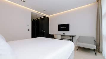 Une chambre d’hôtel comprenant un lit, un bureau, une chaise, une télévision et une porte donnant sur une autre pièce.