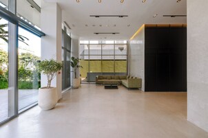 A modern lobby with a sofa, potted plants, and a glass wall.