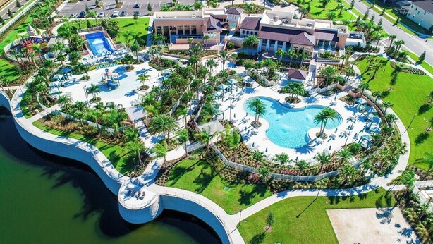 An aerial view of a resort with a large central pool, multiple smaller pools, and a variety of outdoor seating areas surrounded by palm trees and greenery. - 8905 Solara 9bd 22sleep/pool (Davenport)