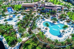 An aerial view of a resort with a large central pool, multiple smaller pools, and lush landscaping. - 8905 Solara 9bd 22sleep/pool (Davenport)