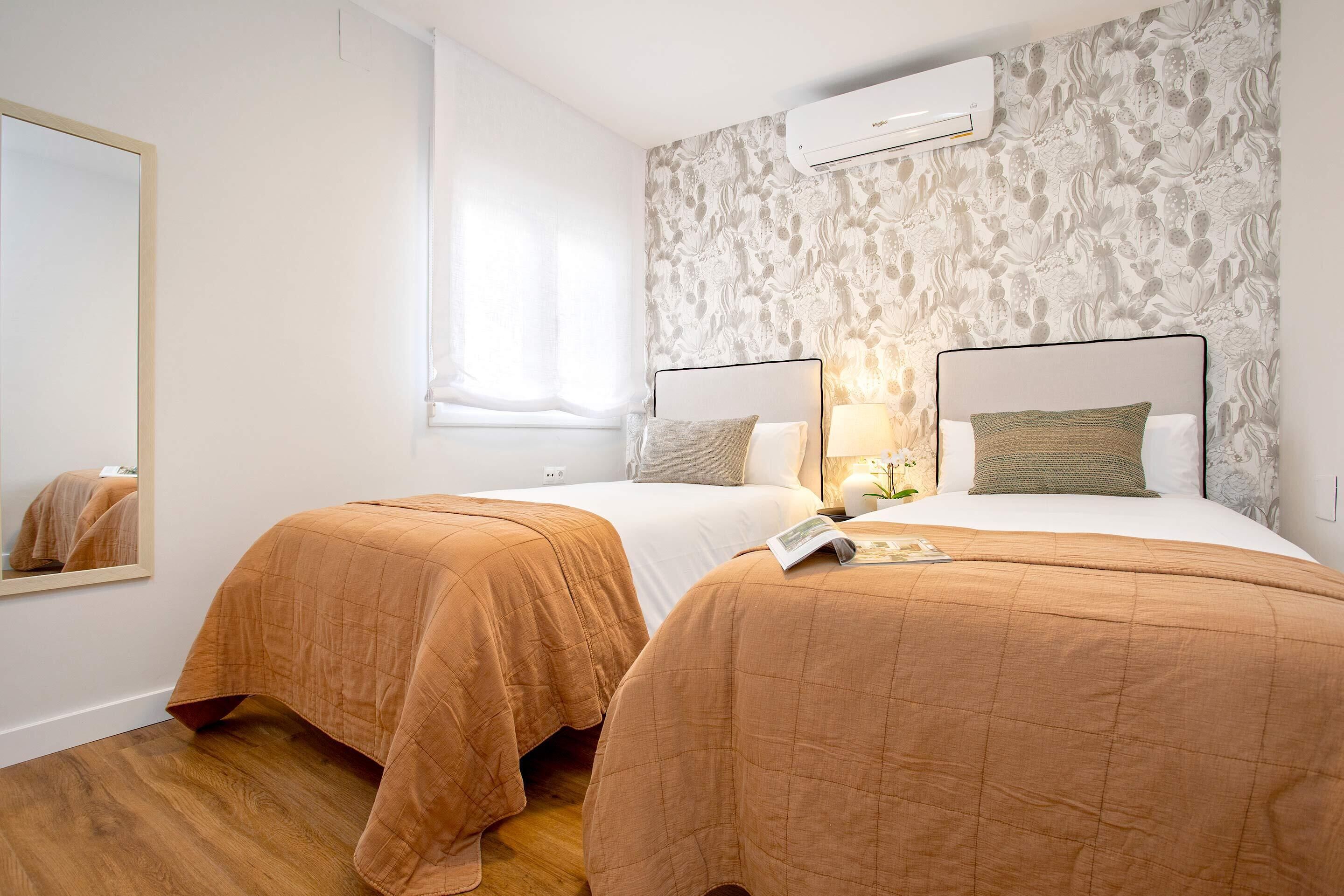 Hotellihuone, jossa on kaksi sänkyä, suuri peili ja ikkuna, jossa on verhot.