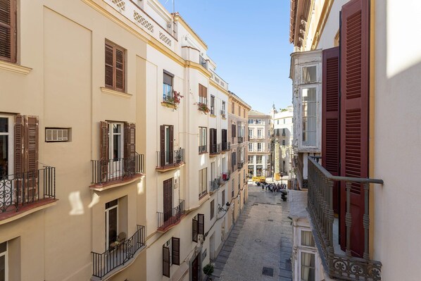 Uma rua estreita com edifícios altos, varandas e um caminho de pedras.