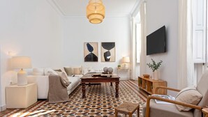 A living room with a patterned floor, a sofa, a coffee table, a TV, and a hanging light fixture. - Luxury Apartment in Malaga. Larios VI (Málaga)