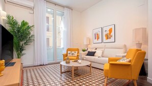 A modern living room with a sofa, armchairs, a coffee table, and a patterned floor.