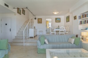 Un salon avec un escalier, un coin repas et une bibliothèque.
