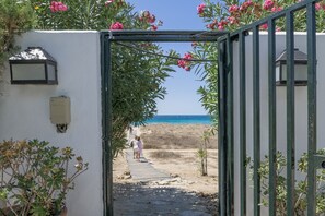 Un sentier menant à une plage, avec une porte, des plantes en pot et un lampadaire.