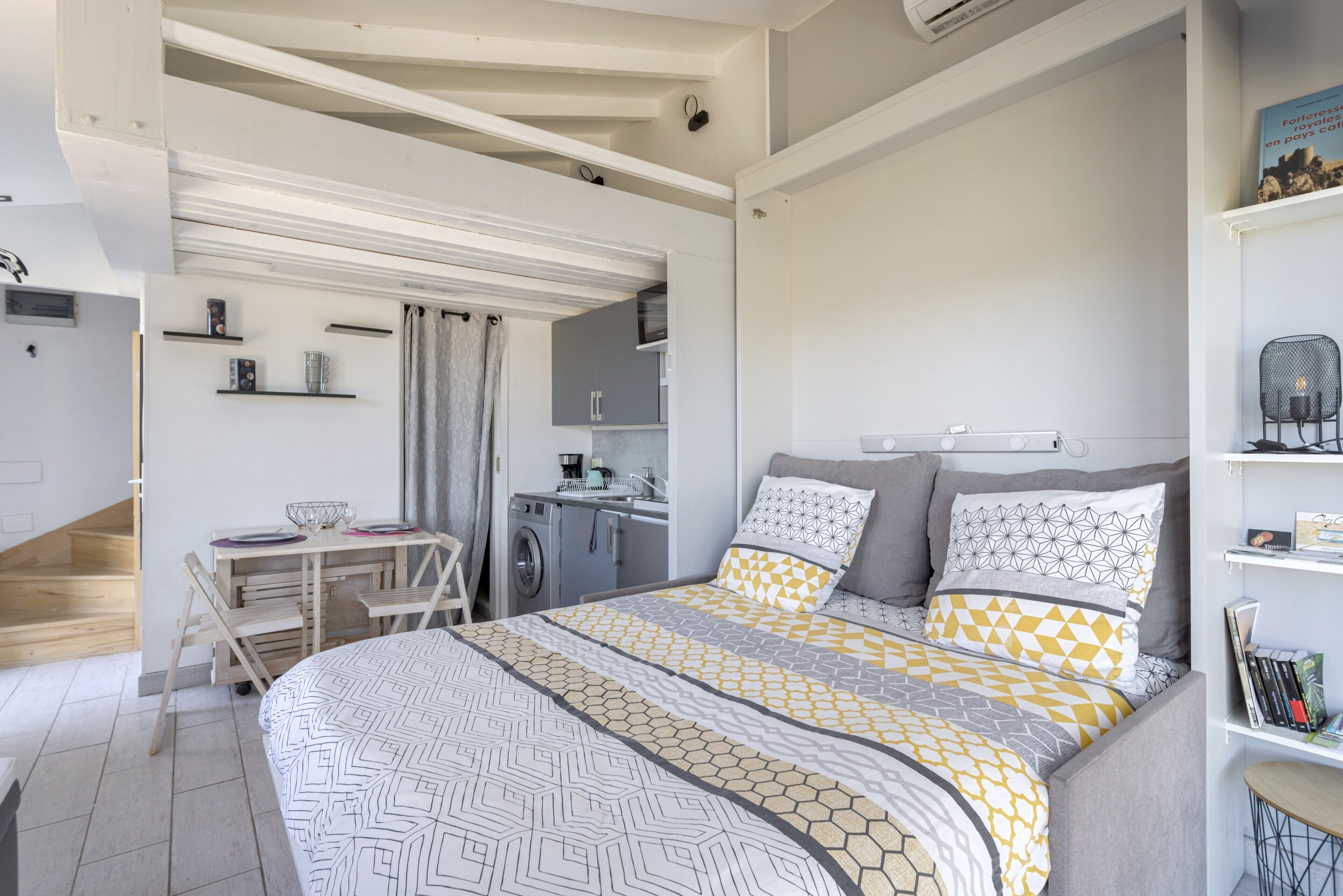 A modern bedroom with a bed, a desk, and a washing machine.