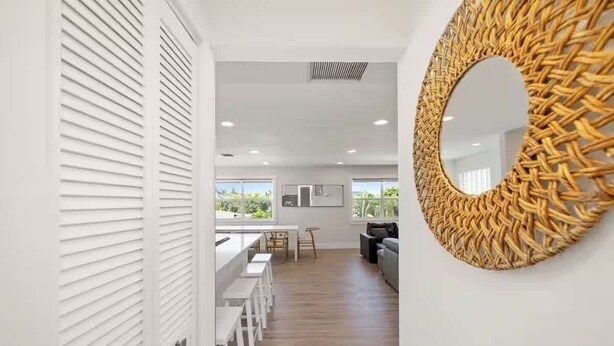 Een modern interieur met een keuken, een eethoek en een zithoek met een grote geweven spiegel.