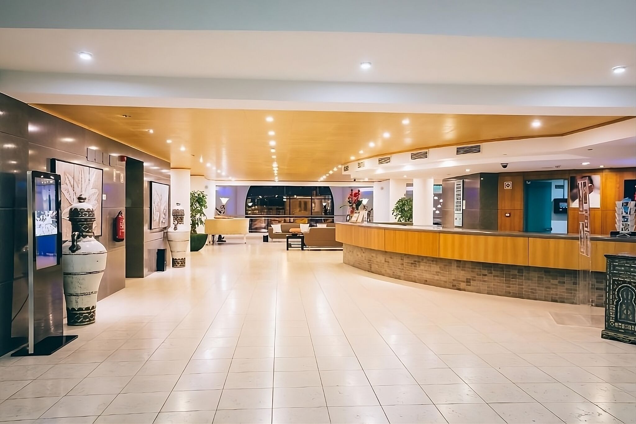 A spacious lobby with a reception desk, seating area, and decorative elements like vases and artwork.