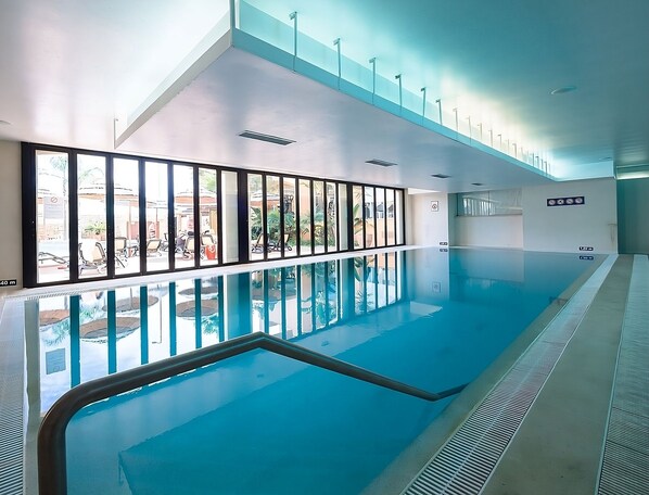 An indoor swimming pool with clear glass walls, a tiled floor, and a ceiling with recessed lighting. - Best Place to Unwind! Free Parking, Full Kitchen, Outdoor and Indoor Pools! (Luz)