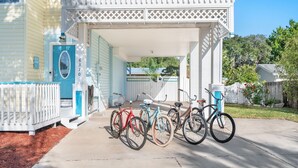 Una casa a due piani con un portico coperto e una porta blu. Sono parcheggiate biciclette davanti.