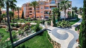 A multi-story hotel with balconies, a landscaped garden, and a paved pathway. - Your Home Away From Home! Fully-equipped Kitchen, 3 Swimming Pool, Free Parking! (Luz)