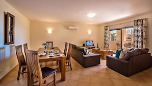 A living room with a dining area, a sofa, and a television.