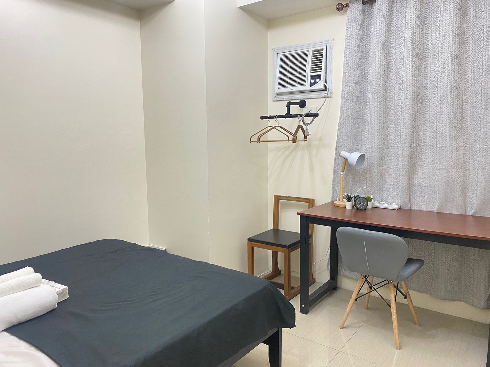 Une petite pièce, bien rangée, avec un lit, un bureau et une chaise.