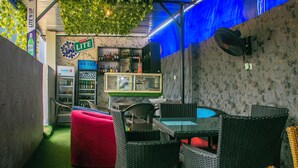 A cozy indoor seating area with wicker furniture, a glass-top table, and a red bean bag. - Glossy Luxury Hotel (Akure)