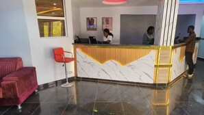 A reception area with a marble counter, red chairs, and a red sofa. - Glossy Luxury Hotel (Akure)