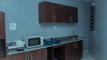 Cocina compacta con microondas, estufa y lavabo.