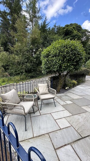 Un patio con due poltrone in vimini e un muro in pietra.