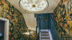 Een trap met bloemen behang, een kroonluchter en een trapleuning.