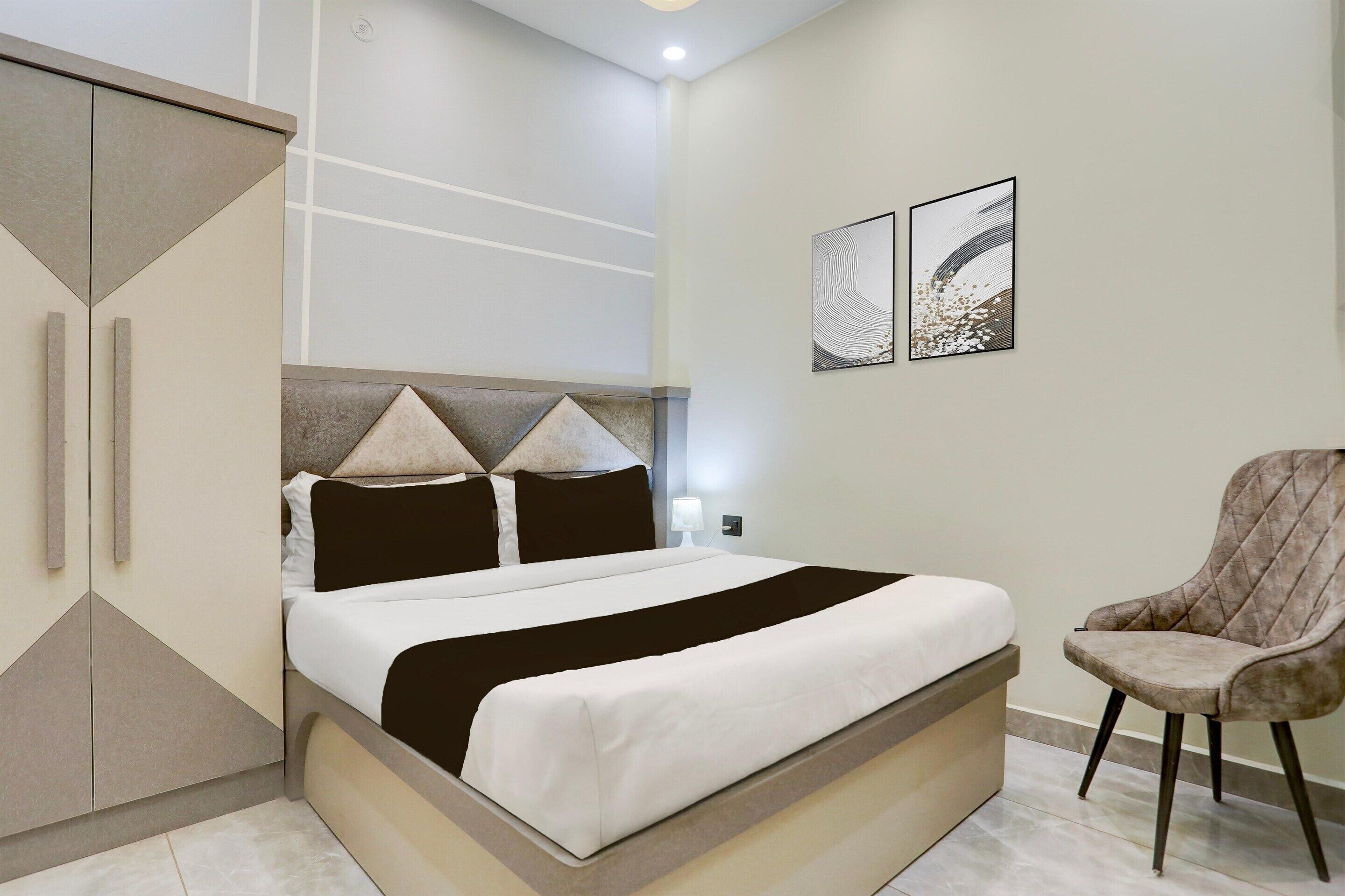 A modern bedroom with a bed, a chair, and artwork on the wall.