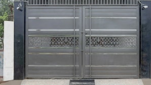 Une grande porte métallique grise, équipée d’une caméra de surveillance et d’un clavier à code.