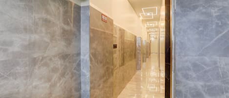 A hallway with marble walls and a fire exit sign.