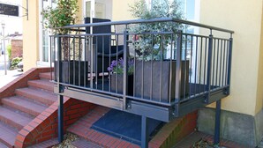 A staircase leading to a balcony with a metal railing, surrounded by potted plants and a building entrance. - Modernes Appartement mit Balkon, Wiek (Wiek)