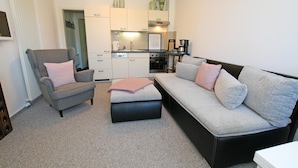 A modern living room with a grey armchair, a grey sofa, and a black ottoman. - Modernes Appartement mit Balkon, Wiek (Wiek)