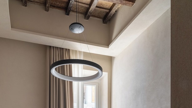 Une chambre moderne avec un grand lit, un luminaire suspendu, une fenêtre avec des rideaux et un plancher en bois.