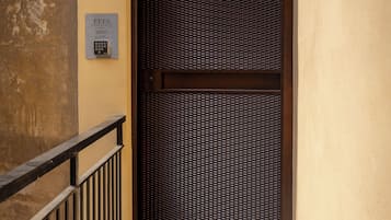 A hotel entrance with a metal gate, a door with a sign, and a keypad for room access.