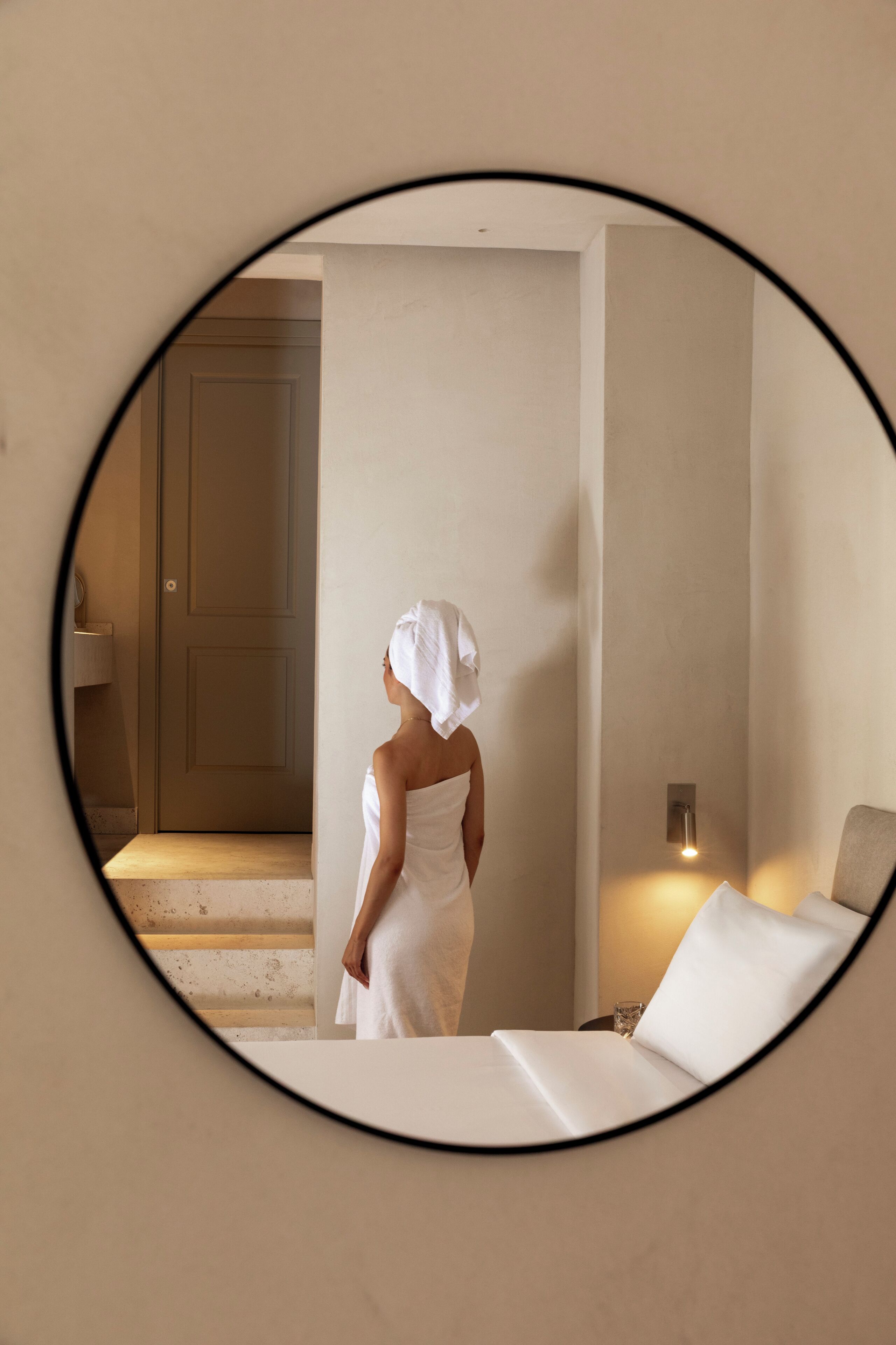Une pièce avec un lit, un miroir fixé au mur et une porte.
