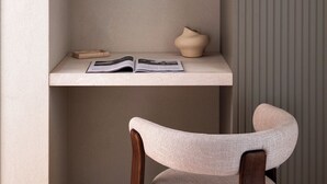 Une pièce au décor minimaliste, avec une étagère intégrée, un luminaire suspendu et une chaise.