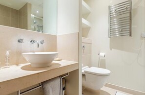 A modern bathroom with a large white sink, a toilet, and a towel rack. - High -Rise waterfront Apartment (London)
