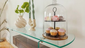 A glass display case with a glass dome, containing three tiers of cupcakes. - High -Rise waterfront Apartment (London)