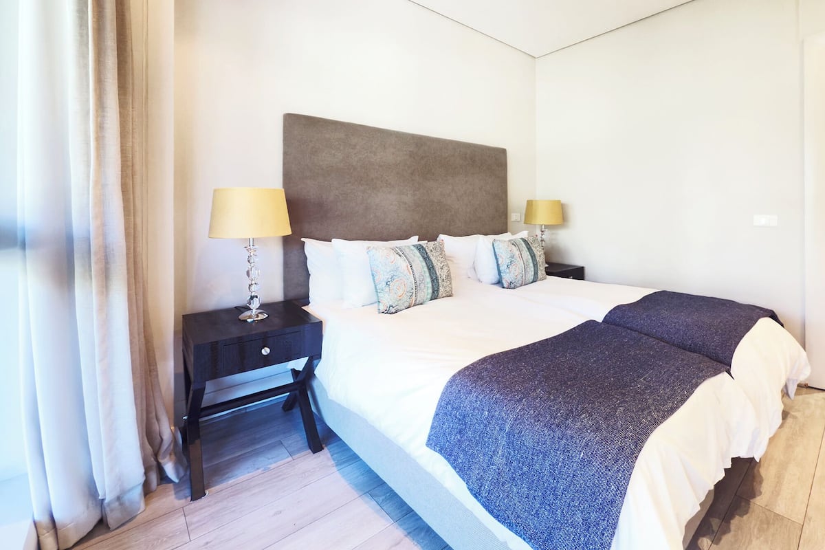 A hotel room with a large bed, two bedside tables, and a headboard.