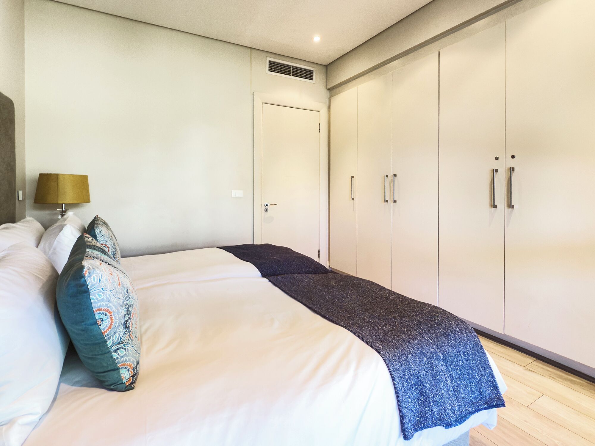 Une chambre à coucher avec un lit, des oreillers, une lampe et une armoire.