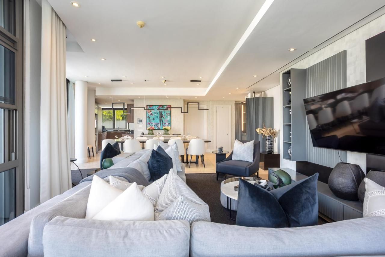 Una sala de estar moderna con un sofá grande, un televisor de pantalla plana y un área de comedor al fondo.