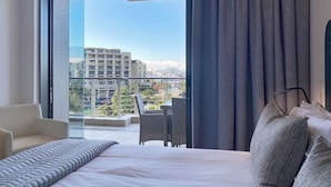 A hotel room with a bed, a chair, and a view of the cityscape through a large window. - The Marina V&A Waterfront by Smart City Stays (Cape Town)