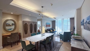 A modern living room with a dining area, featuring a marble table, green chairs, and a sofa with cushions. - The Marina V&A Waterfront by Smart City Stays (Cape Town)