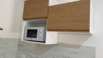 Una cucina con forno a microonde integrato, mobili in legno e piani di lavoro in marmo.