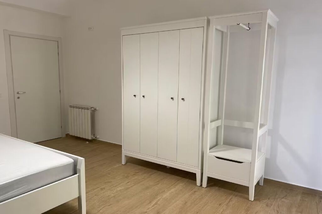 Ein Zimmer mit einem weißen Wandschrank, einem Heizkörper und einem Bett.
