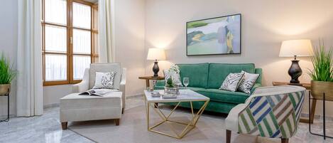 Uma sala de estar moderna com um sofá verde, duas poltronas, uma mesa de centro e duas luminárias.