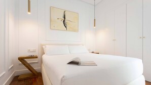 A modern bedroom with a large bed, a bedside table, a wall-mounted artwork, and a hanging light fixture. - Modern Apartment in Seville. Corral del Rey II (Seville)