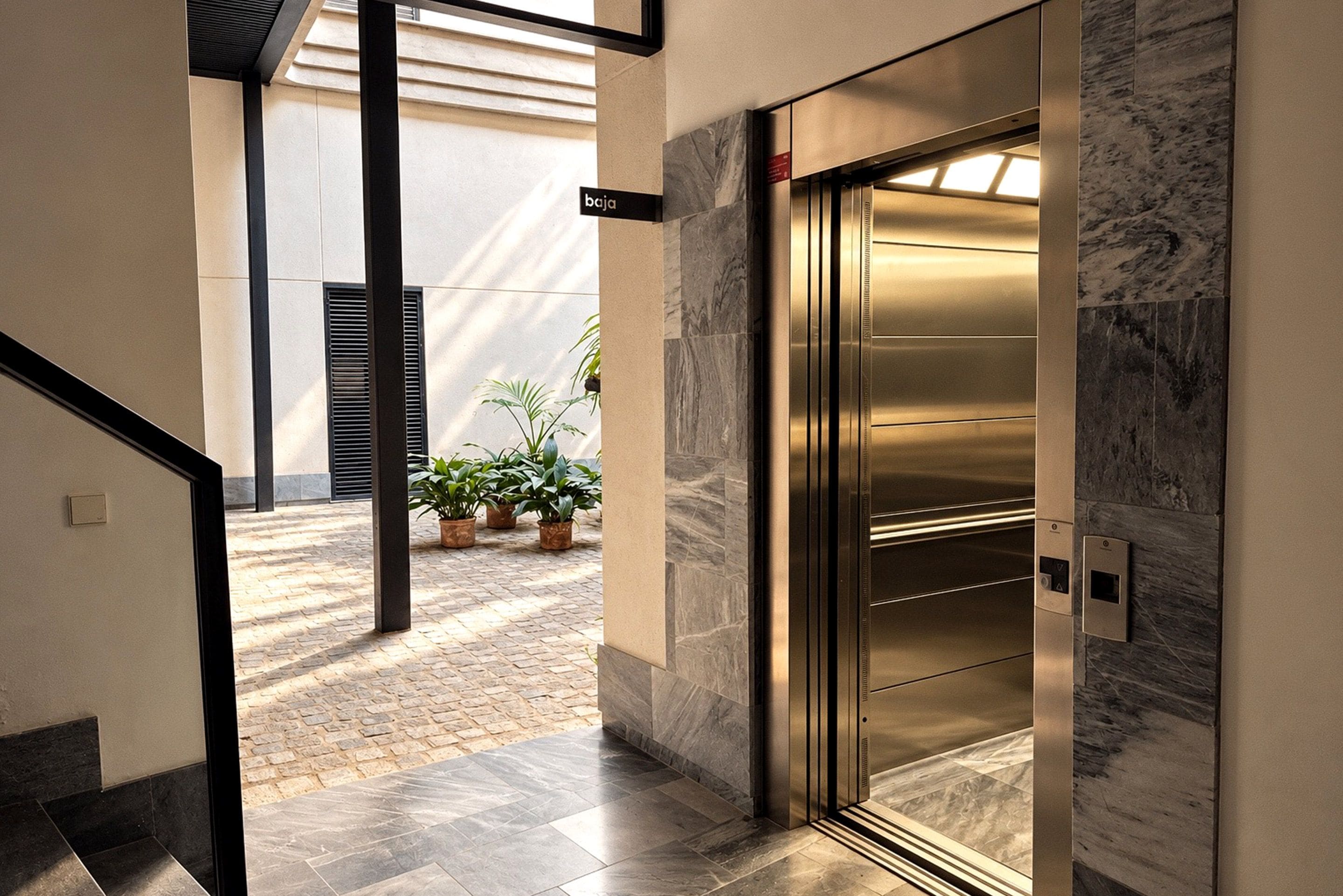 An elevator with a marble wall, a sign indicating the floor level, and a potted plant in the background.