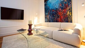 A modern living room with a large abstract painting, a flat-screen TV, and a glass coffee table. - Modern Apartment in Seville. Corral del Rey II (Seville)