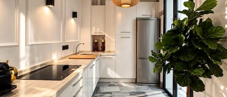 Una cocina moderna con un refrigerador de acero inoxidable, horno empotrado y un amplio ventanal que proporciona luz natural.