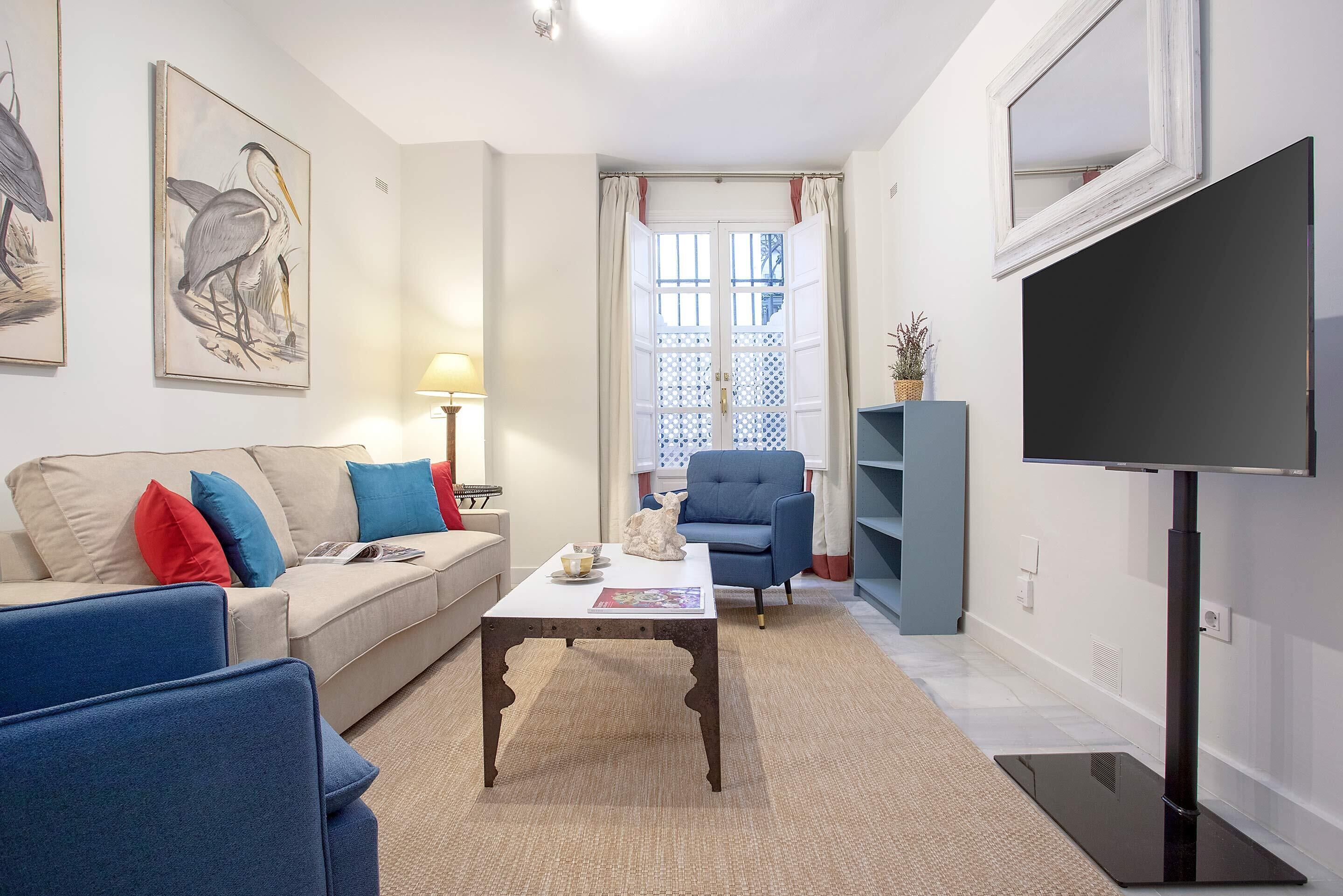 A living room with a sofa, armchair, coffee table, and a flat-screen TV.