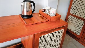 Een houten tafel met een waterkoker, twee mokken en een lepel op een dienblad.