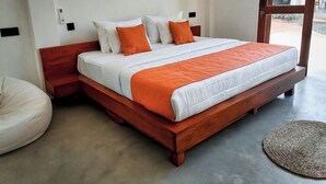 Een moderne slaapkamer met een houten bedframe, witte beddengoed en oranje accenten.