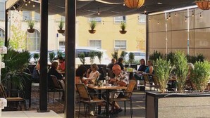 An outdoor cafe with tables and chairs, potted plants, and a covered seating area. - The Urban Alchemist Loft (Benton Harbor)